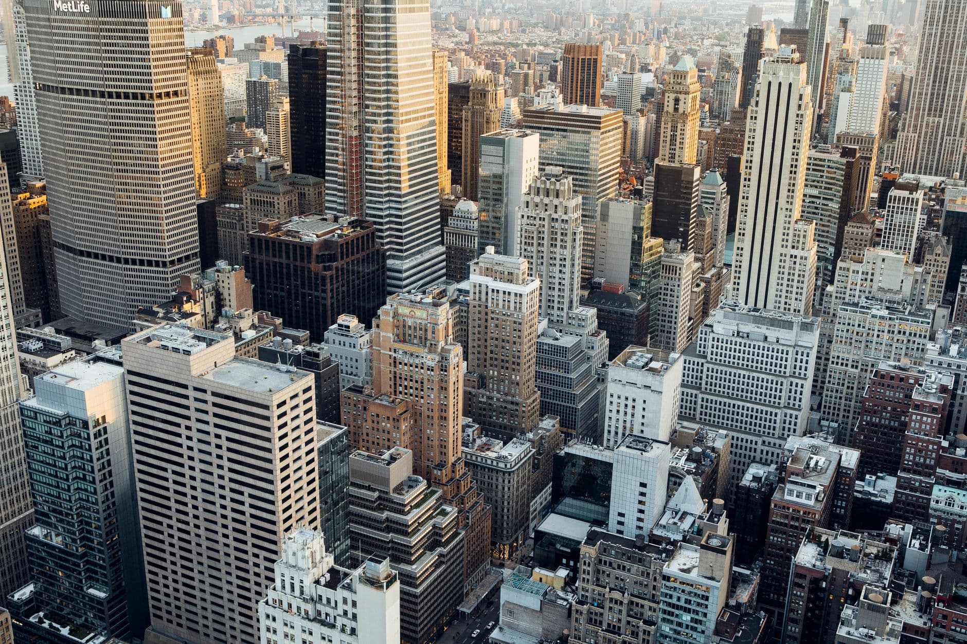High aerial view of Midtown Manhattan in morning light, with tightly packed office towers receding toward the East River.