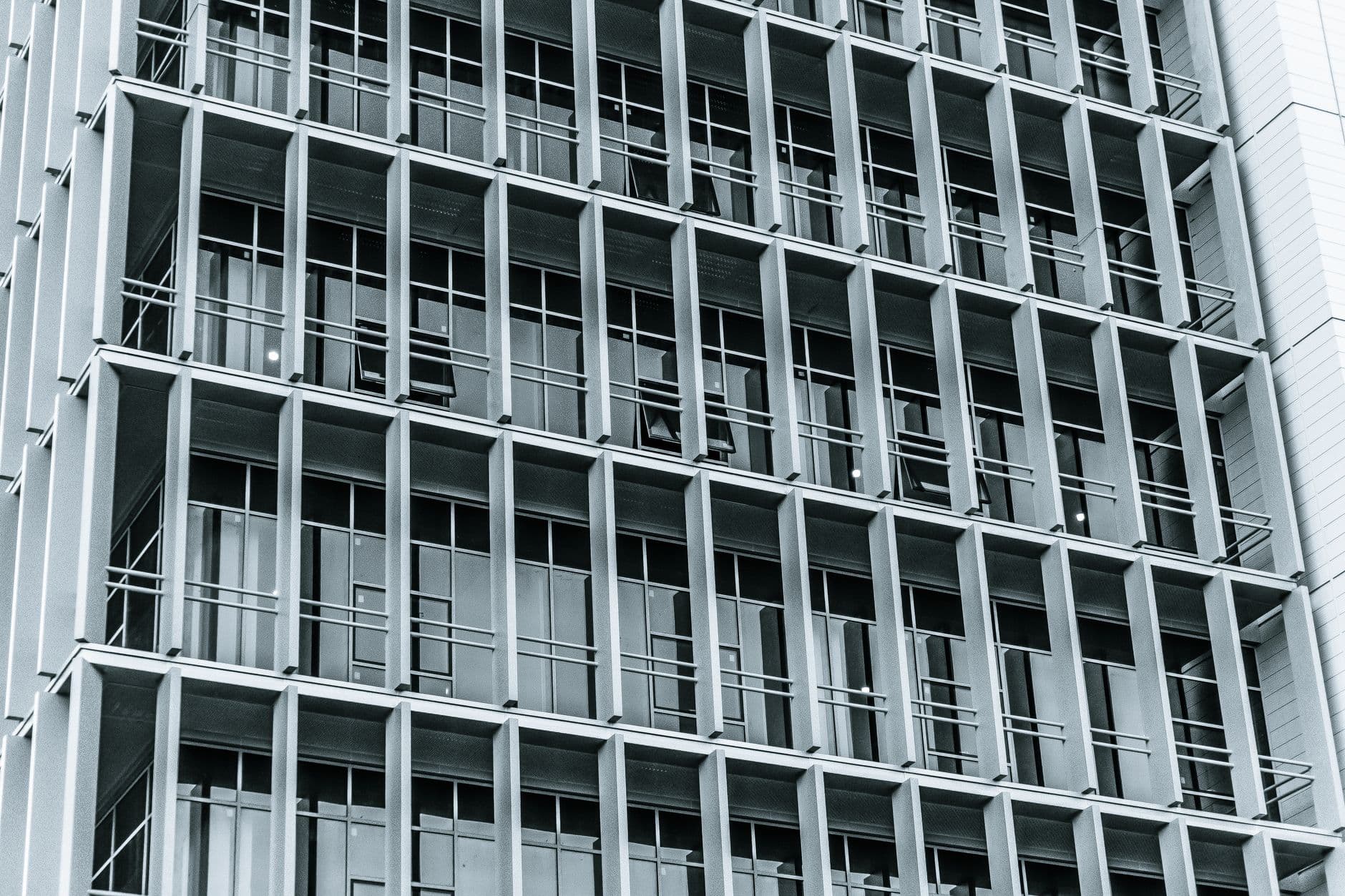 Repeating grid of recessed window bays on a high-rise facade rendered in muted gray tones.